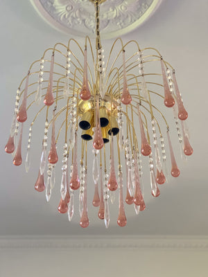 Chandelier with pink and clear glass droplets on a ceiling.