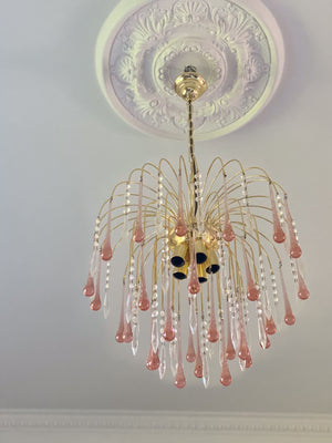 Decorative chandelier with pink and clear crystals on a ceiling with intricate design.