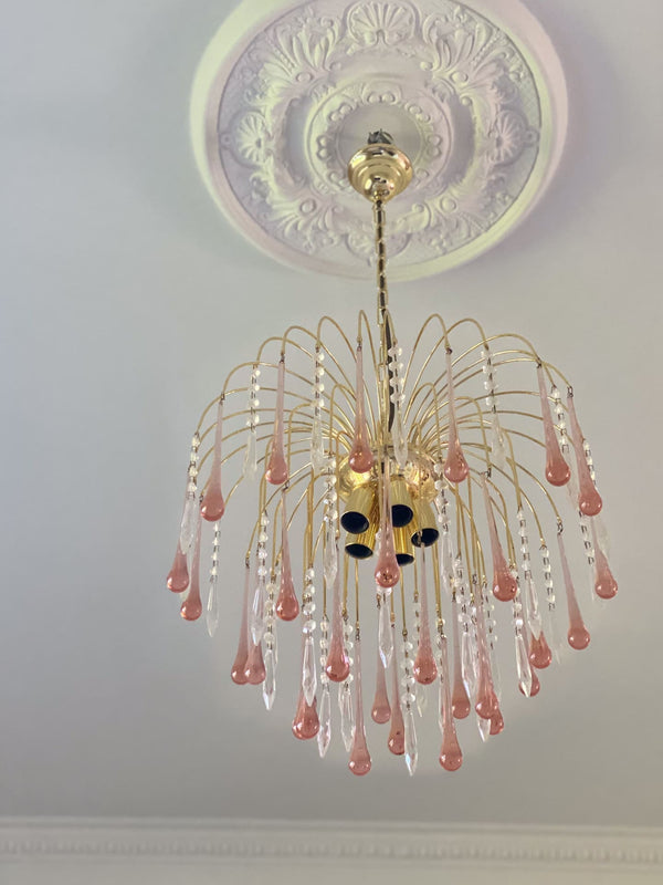 Decorative chandelier with pink and clear crystals on a ceiling with intricate design.